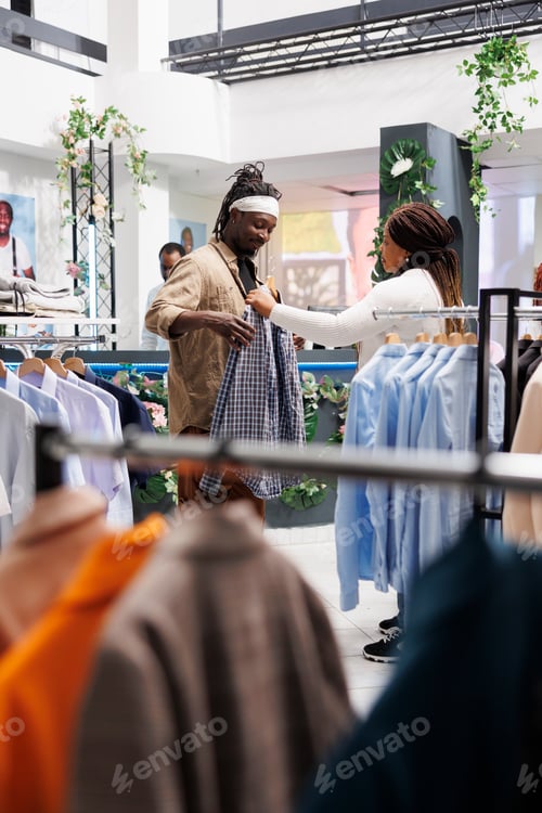 Preview: Woman helping man choosing shirt, giving outfit to try