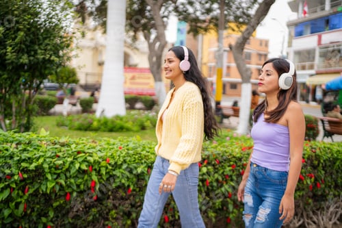 Preview: Two young women walking and listening music in a park
