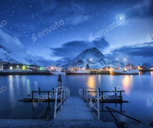 Preview: Fishing boats near pier on the sea and snowy mountains at night