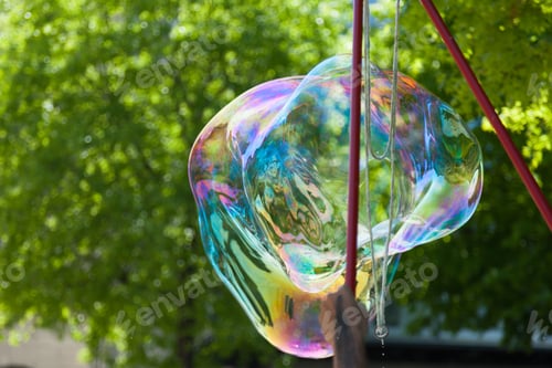 Preview: Arstist blowing colorful giant soap bubbles outdoor
