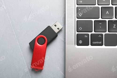 Preview: Modern flash drive and laptop on light grey table, flat lay