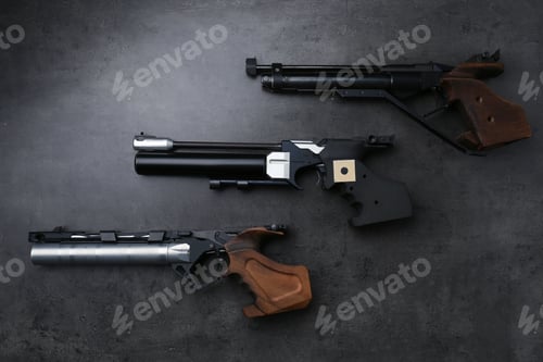 Preview: Many different sport pistols on black table, flat lay. Professional guns