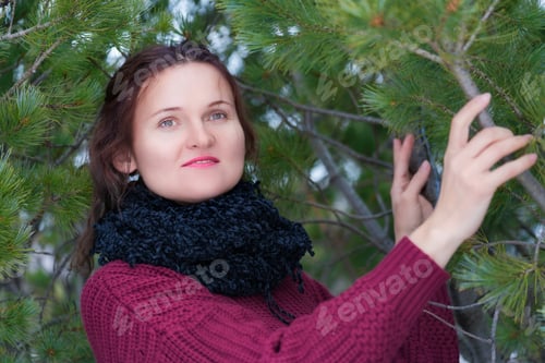 Preview: Brunette Woman with Long Hair Dressed in Brown Pullover and Black Scarf Standing in Pine Forest