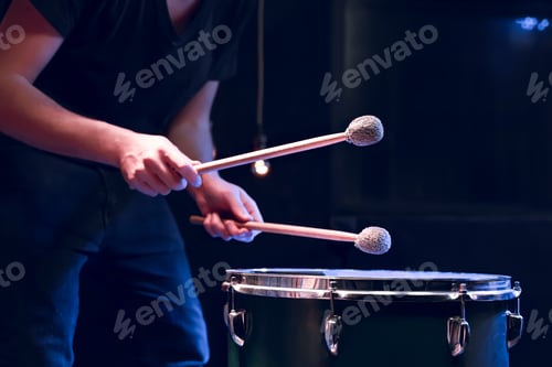 Preview: The drummer plays with mallets on floor tom in dark room.