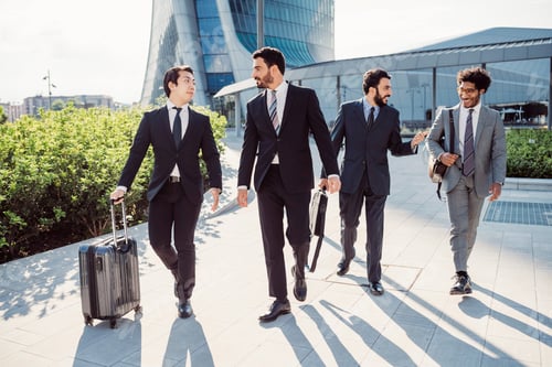 Preview: Business professionals walking confidently in an urban setting with luggage.