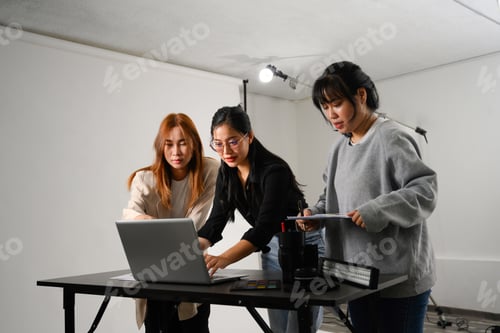 Preview: Young creative people using laptop working together in a professional studio