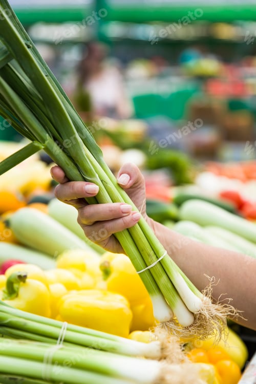 Preview: Woman buying bunches of spring onions on stall at the market