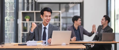 Preview: Portrait of confident young businessman using laptop while colleague in background