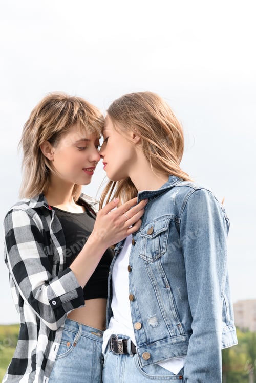 Preview: young lesbian couple kissing with eyes closed outdoors