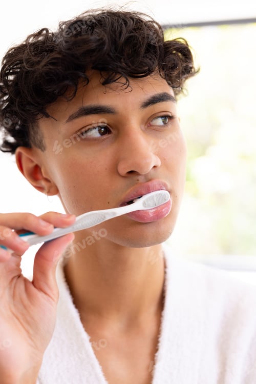Preview: Brushing teeth, young young man in white robe focusing on oral hygiene