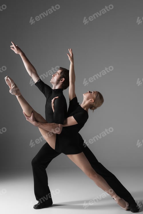 Preview: The Two Young Modern Ballet Dancers In Black Suits Posing Over Gray Studio Background