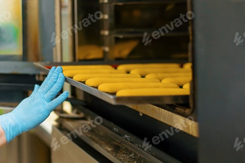 Preview: Kitchen in a bakery - eclairs on a baking sheet before baking in bakery