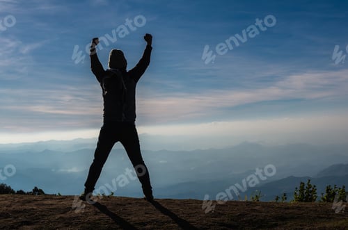 Preview: silhouette of a man who show hands over the mountains landscape