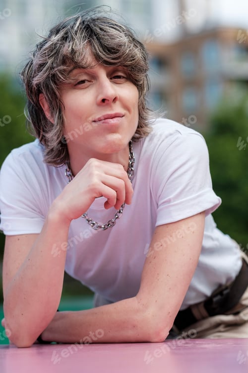 Preview: Young stylish person leaning on pink surface in urban setting