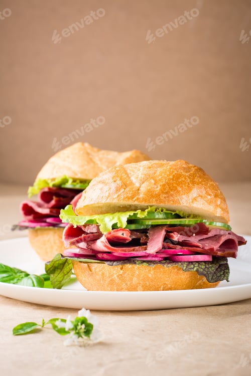 Preview: Ready-to-eat hamburger with pastrami, vegetables and basil on a plate on craft paper