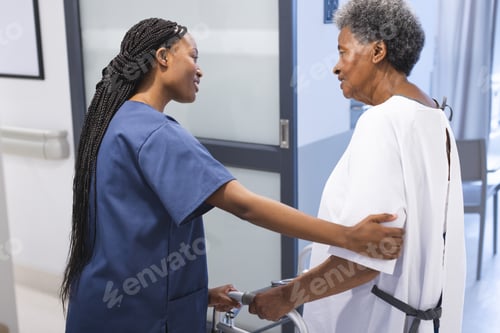 Preview: African american female doctor talking with senior female patient with crutches in hospital corridor
