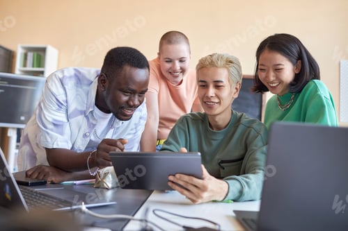 Preview: Group of happy intercultural students discussing data on screen of tablet
