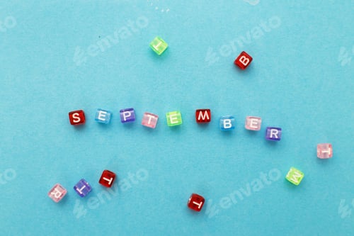 Preview: inscription September made by multicolor plastic cubes on a blue background.