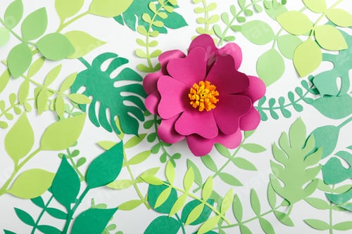 Preview: top view of pink paper flower and green leaves on white background