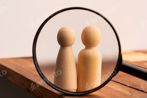 Preview: Two wooden figures of people through magnifying glass. Search of love concept