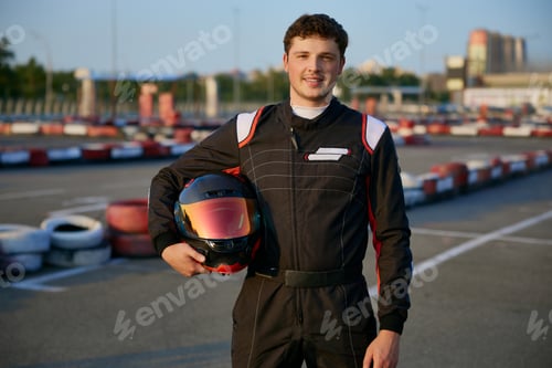 Preview: Smiling Man Holding Helmet on Race Track