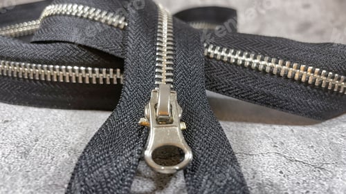 Preview: Closeup of a black zipper over the grey background