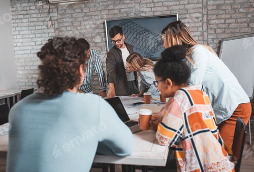 Preview: Group of modern business people in casual wear discussing architectural designs in the office.