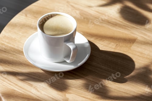Preview: A white porcelain cup with coffee on a saucer stands on a round table