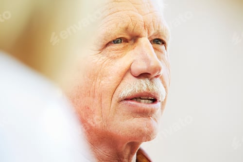 Preview: Portrait of a senior man with moustache sitting outdoors.