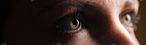 Preview: close up view of human eye looking away in dark, panoramic shot