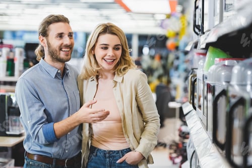 Preview: smiling consultant pointing with finger at microwave and talking with woman in home appliance store