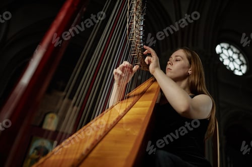 Preview: Professional Female Musician Playing Harp Plucking Strings while Performing Music in Church