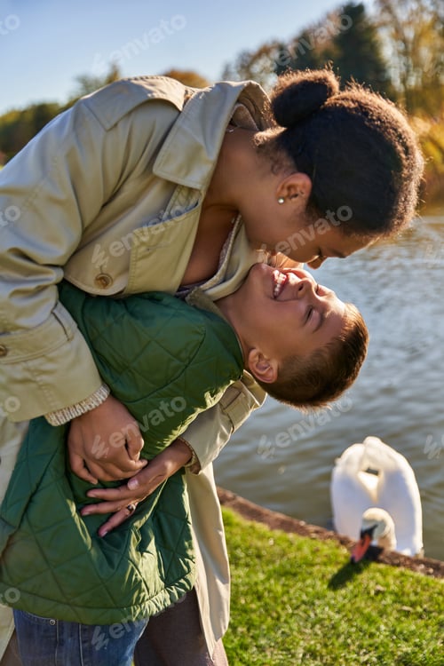 Preview: family bond, love, happy african american mother and child hugging near lake, nature, autumn, fun