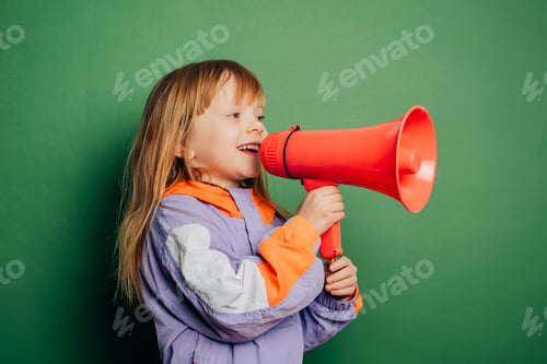 Preview: little red-haired girl in a vintage jacket holds a megaphone against a green background