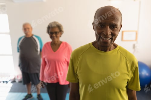 Preview: Front view of happy senior friends looking at camera in fitness studio