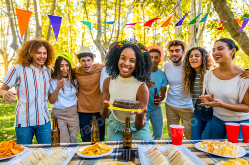 Preview: African woman celebrating birthday with cake during picnic with friends