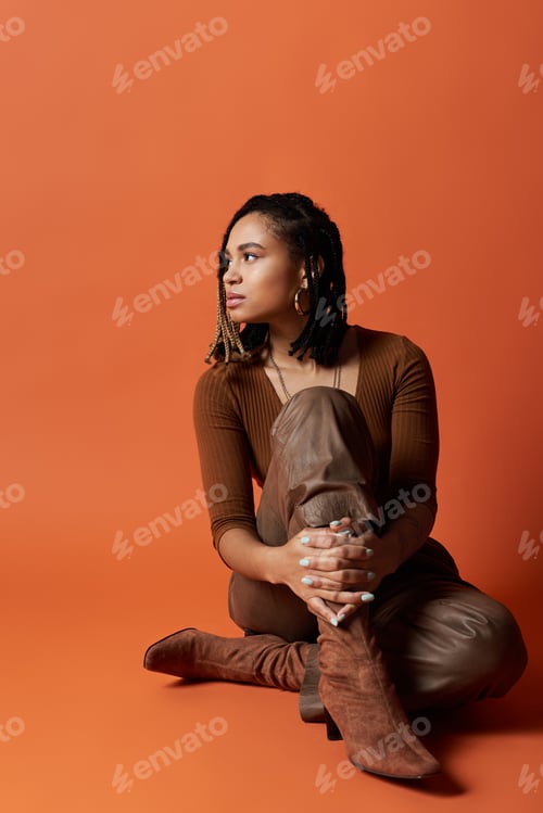 Preview: Stylish young African American woman with braids poses in a vibrant studio