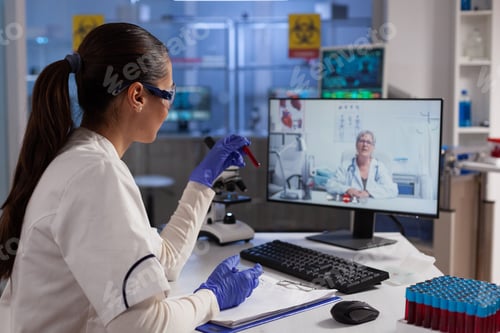 Preview: Therapist doctor holding test tube with infected blood discussing with remote doctor