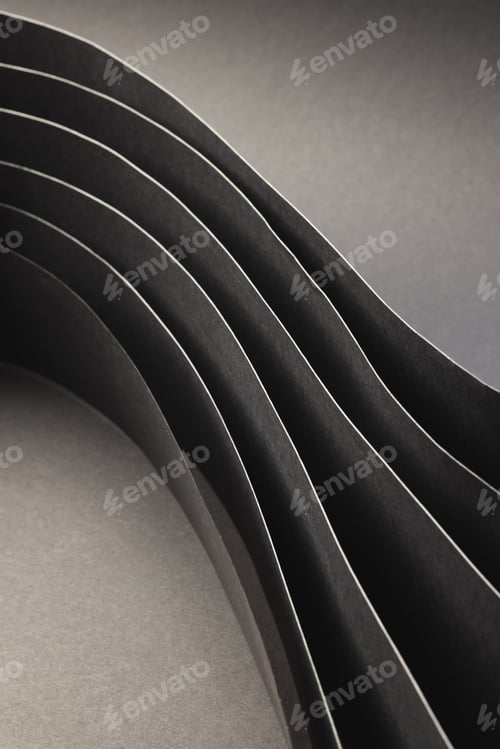 Preview: Vertical image of close up of rolled up pieces of black paper with copy space on grey background