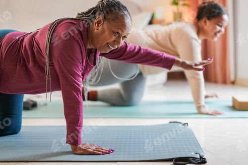 Preview: African mother and daughter doing yoga class together at home during winter season