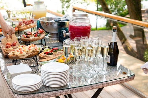 Preview: Outdoor catering table set with champagne, fruit punch, and appetizers
