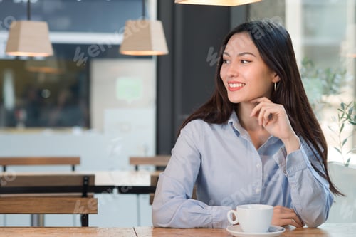 Preview: Pretty Caucasian female looking aside in a cafe