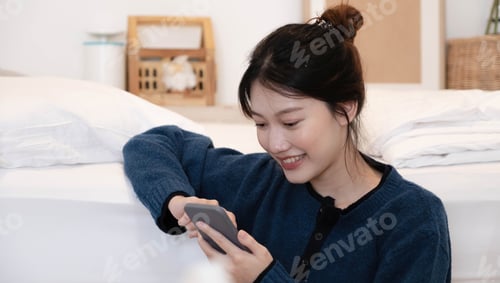 Visualização: Linda mulher usando um telefone inteligente pela manhã na cama em casa