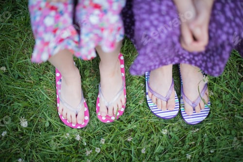 Preview: Girls in flip flops standing on green grass during summer