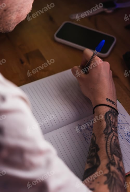 Preview: Hands of a creative editor jotting down ideas in his notebook on the desk