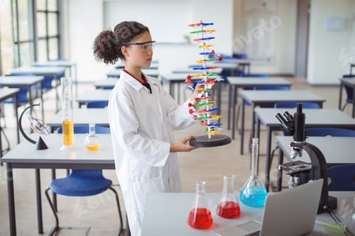 Preview: Attentive schoolgirl experimenting molecule model in laboratory