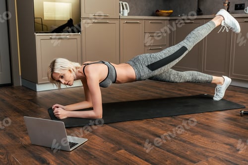 Preview: young sportswoman having online training on laptop at home during quarantine