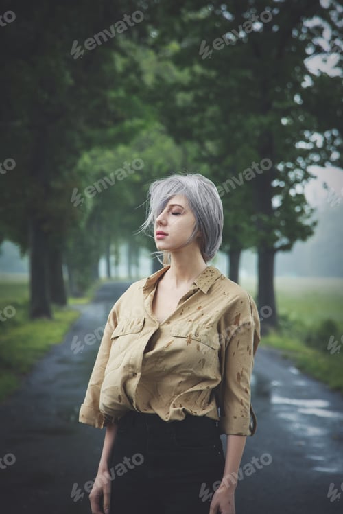 Vista previa: Blonde girl in depression at countryside road in rainy day