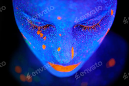 Preview: Beauty shines brightest in the dark. Shot of a young woman posing with neon paint on her face.
