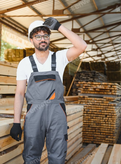 Preview: Carpenter adjusting helmet in lumber warehouse, woodworking industry portrait
